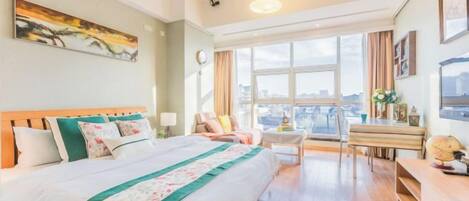 Una camera d'albergo con un letto grande, una scrivania, una sedia e vista sulla città da ampie finestre.