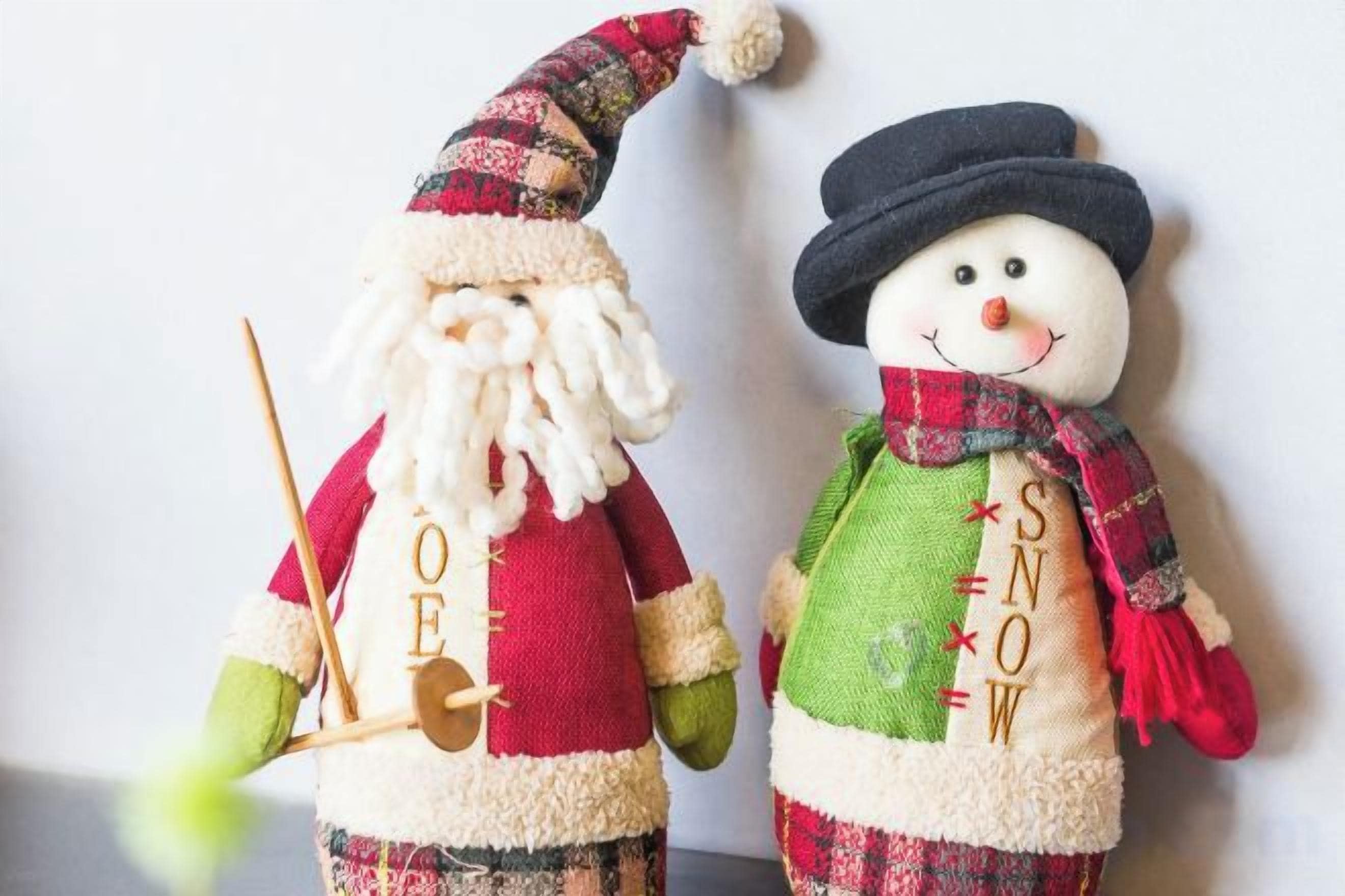 Dos peluixos de Nadal, un amb aspecte de Pare Noel i l'altre d'home de neu, amb textos i accessoris.