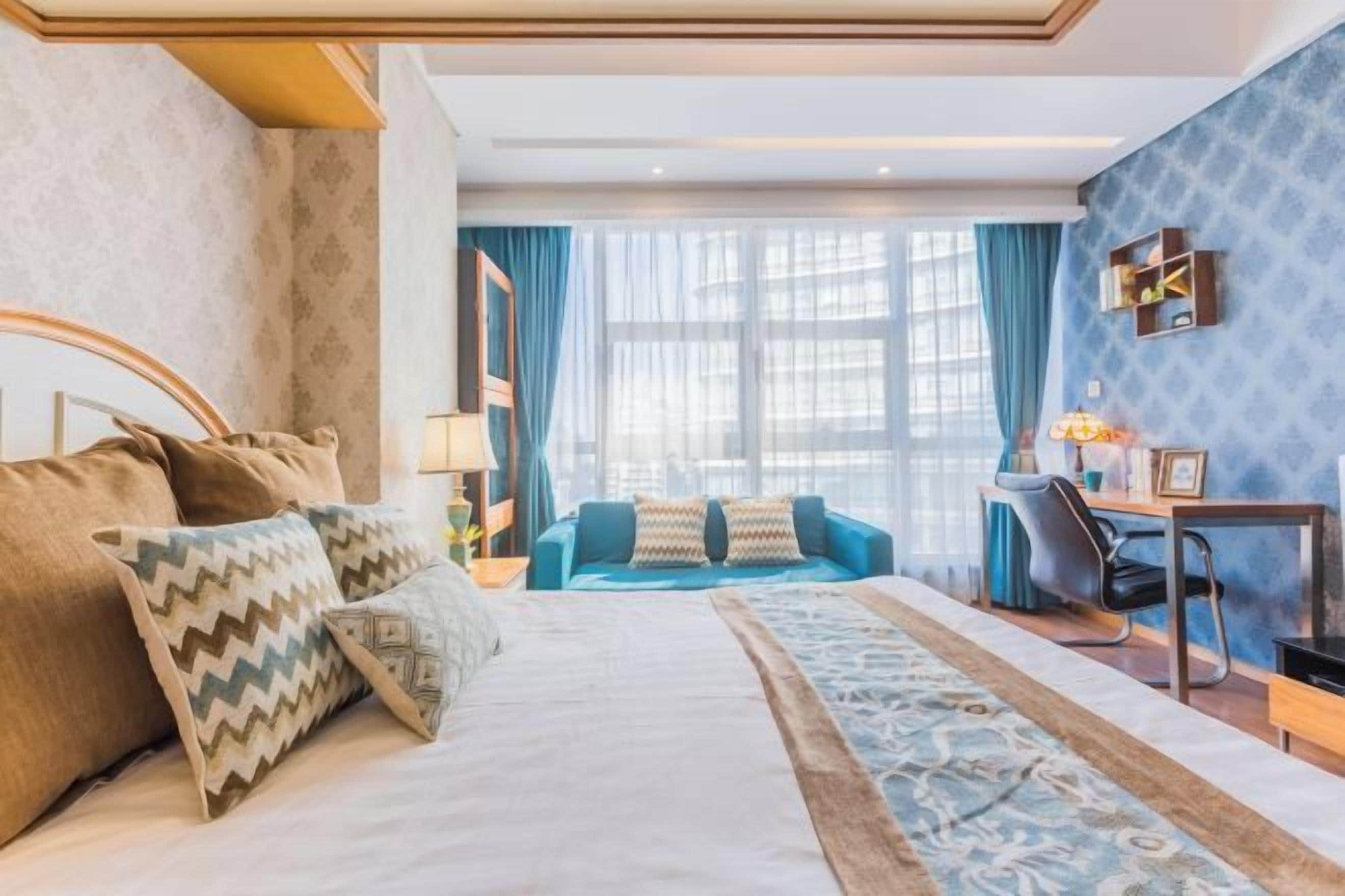 Ein Hotelzimmer mit einem großen Bett, einem Schreibtisch, einem Stuhl und Blick auf die Stadt.