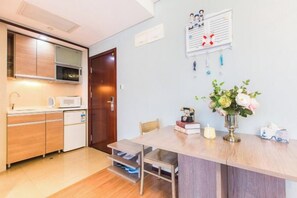 Une cuisine compacte dotée d’appareils électroménagers modernes, un coin repas avec une table et des chaises, et un petit réfrigérateur.