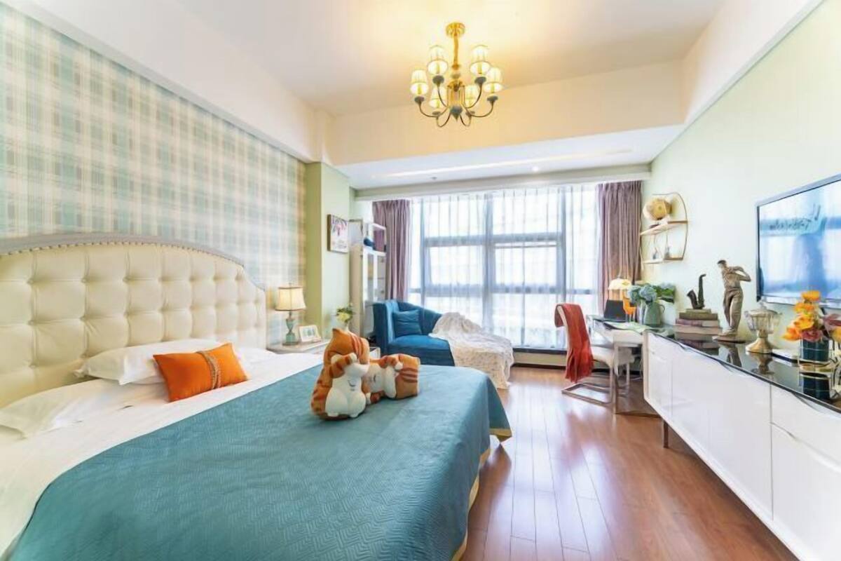 Ein Hotelzimmer mit einem großen Bett, einem Schreibtisch, einem Stuhl und einem Fernseher.