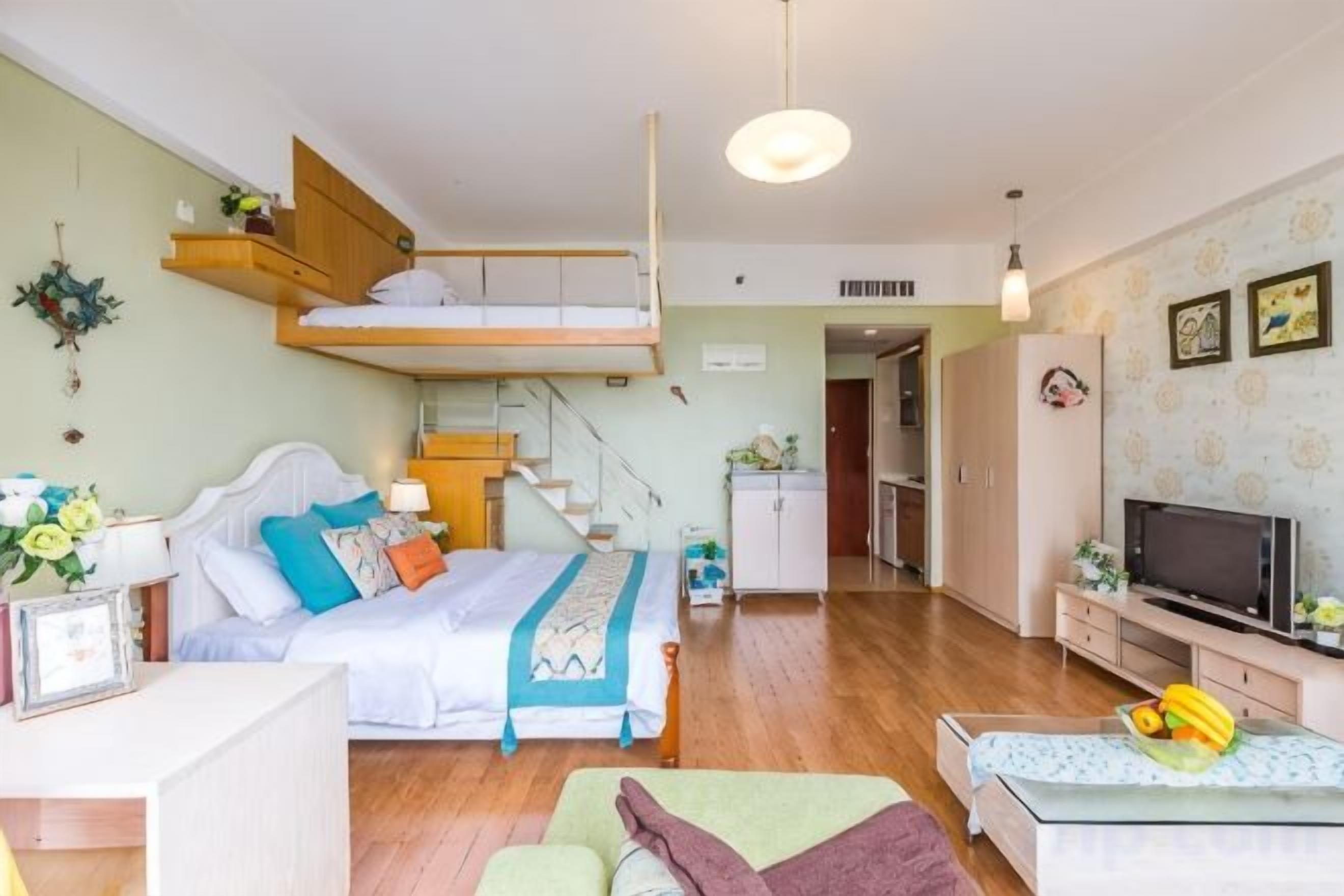 A room with a bunk bed, a desk with a chair, a television, and a dining area.