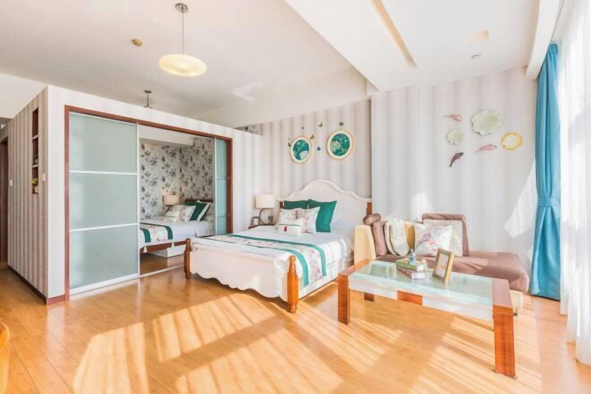 Ein Schlafzimmer mit einem Bett, einem Glastisch, einem Kleiderschrank und einer Wand mit dekorativen Tellern.