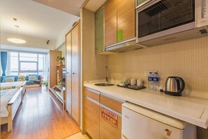 A compact kitchen with a microwave, kettle, and sink.