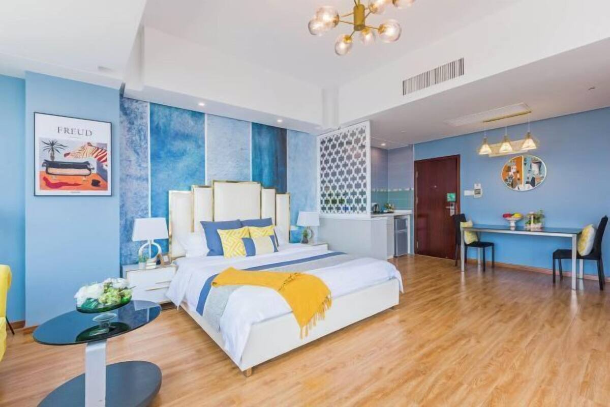 Ein modernes Hotelzimmer mit einem großen Bett, Nachttischen, einem Schreibtisch und einer Sitzecke.