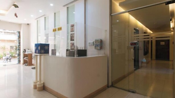 A reception desk with glass partitions, a sign indicating a 'No Smoking' policy, and a glass door leading to another area. - RedDoorz @ TJMG by Bel Air Polaris Makati (Makati)