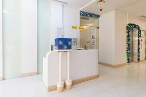 A reception desk with a blue box, a sign indicating a waiting area, and a Christmas decoration. - RedDoorz @ TJMG by Bel Air Polaris Makati (Makati)