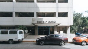 Un edificio con un letrero que dice 'bel-air soho' y un estacionamiento con coches.