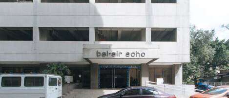 A building with a sign reading 'bel-air soho' and a parking lot with cars.