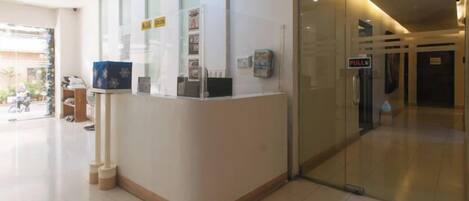A reception area with a glass partition, a reception desk, and a sign indicating a rest area.
