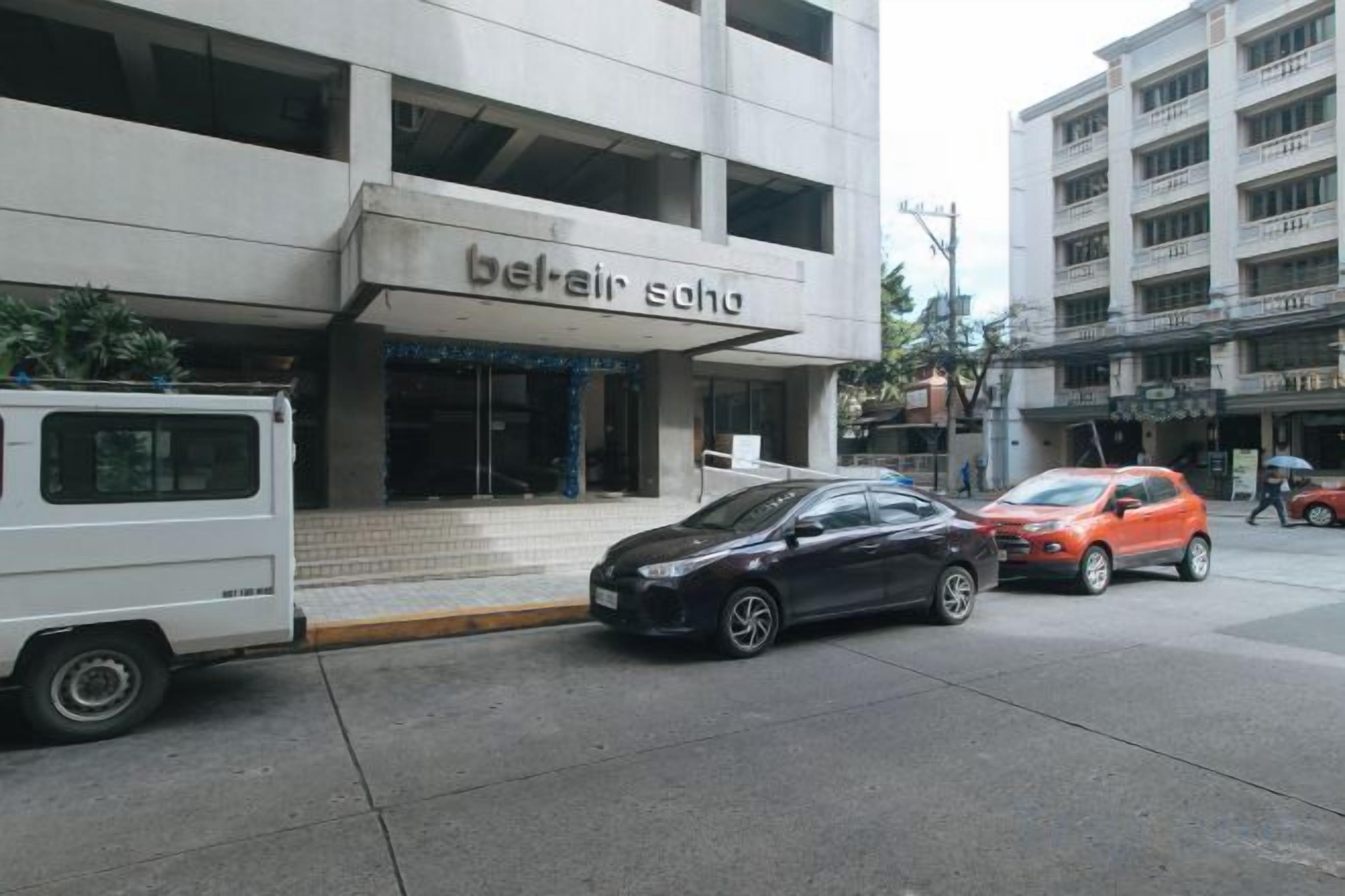 A building with a sign that reads 'bel-air soha' and a parking area with cars.