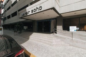 Ein Gebäude mit einem Schild, auf dem 'Bel Air Soho' steht, und einer Treppe, die zum Eingang führt.