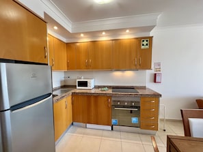 Kitchen equipped with a sink, microwave, and small oven, along with a refrigerator.