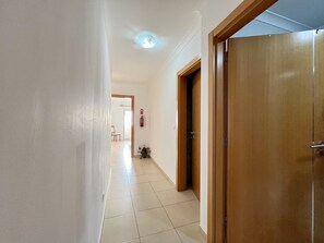 Stylish hallway leading to a cozy room with a bed and window.