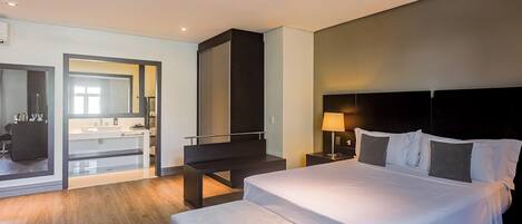 Una habitación de hotel con cama, mesita de noche, lámpara y vista al baño.