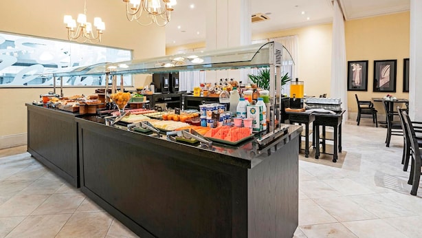 A buffet area with a variety of food items and beverages, a glass display case, and a seating area with tables and chairs.