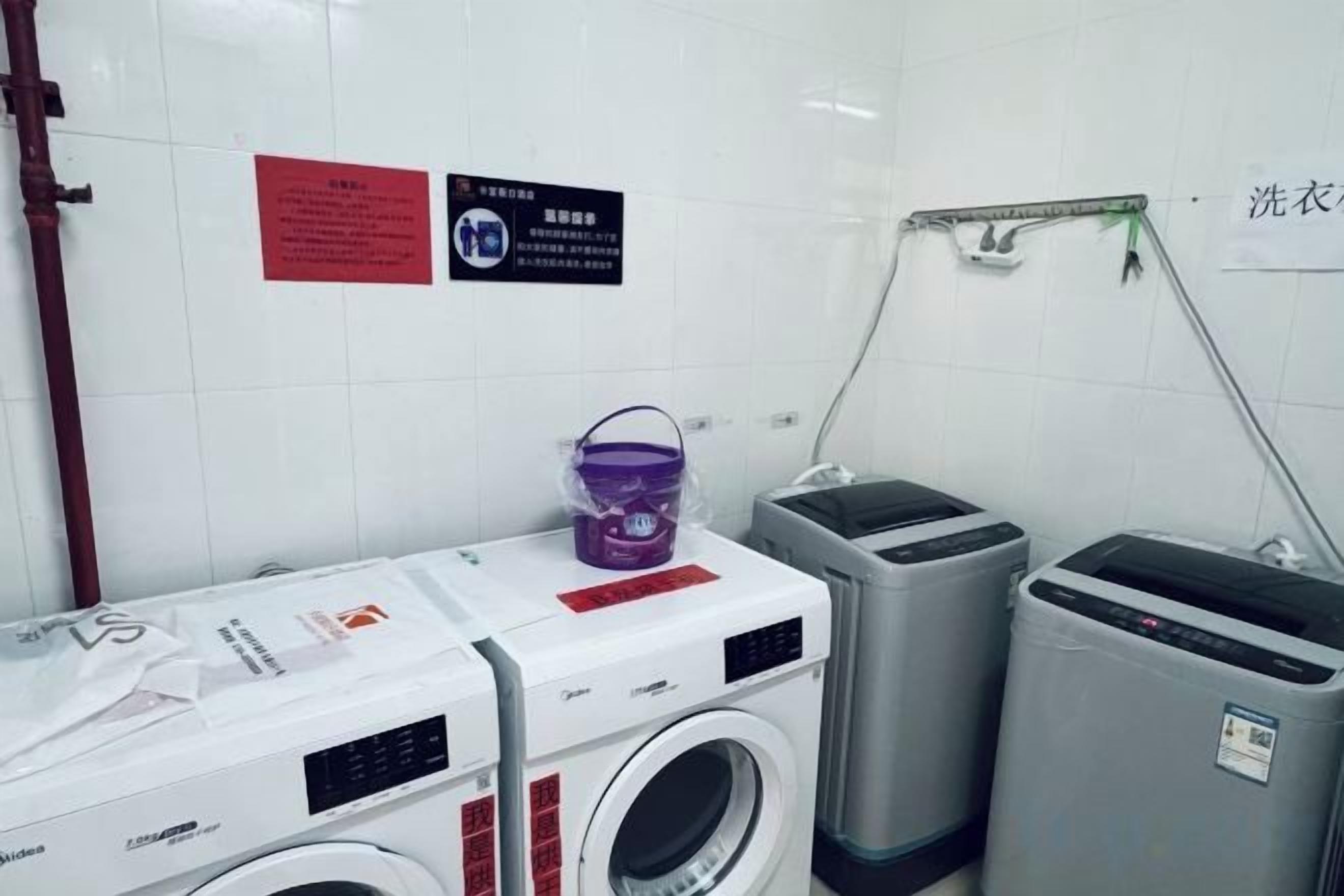 Un cuarto de lavandería con lavadoras, secadora y un balde.