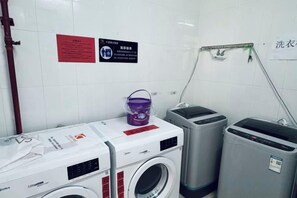 A laundry facility with washing machines, a drying machine, and a bucket. - Kayi Hotel (Dongguan)