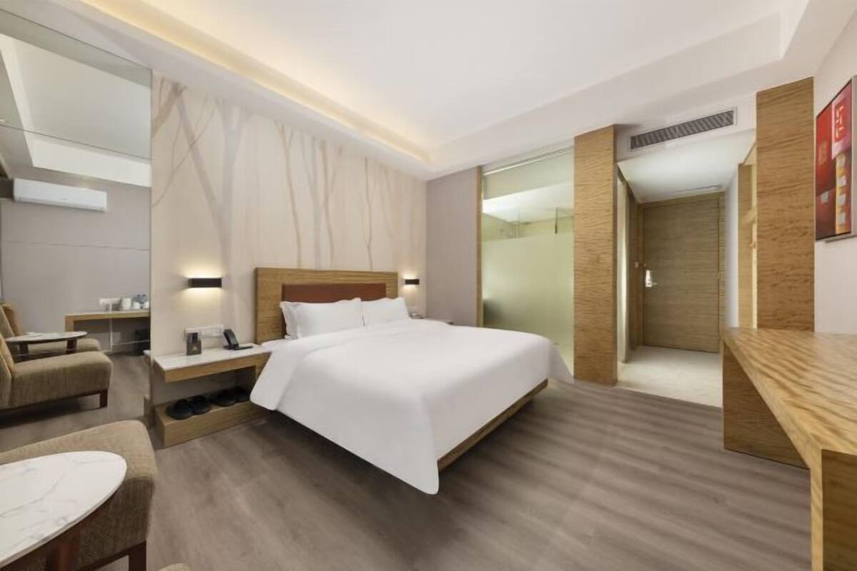 A modern hotel room with a large bed, bedside tables, a desk, and a chair.