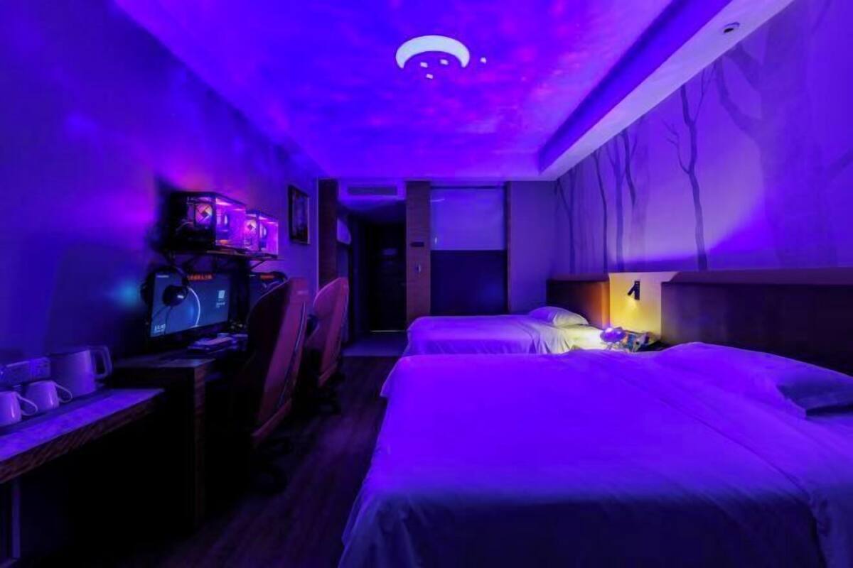 A room with a bed, a desk with a computer, and a wall-mounted TV.