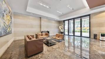 A spacious lobby with a marble floor, modern furniture, and large windows offering a view of the outdoors.