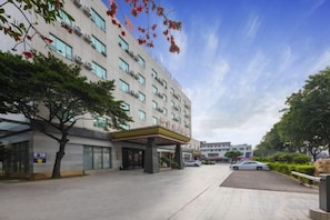 A hotel with a covered entrance, multiple floors, and a parking area. - Kayi Hotel (Dongguan)