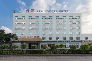 En hotellbyggnad med flera våningar, med en skylt som visar texten ”KAYI HOLIDAY HOTEL” och en mindre skylt under den.