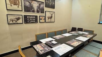 Un salón de conferencias con una mesa larga, sillas e imágenes enmarcadas en la pared.