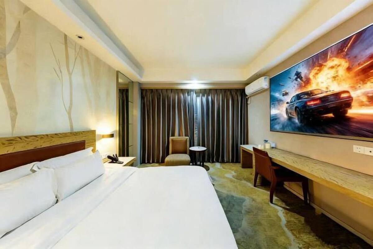 A hotel room with a bed, a desk, a chair, a TV, and a curtain.