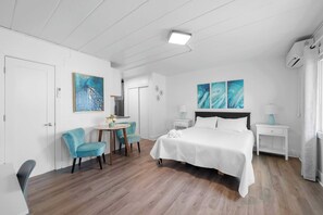 A hotel room with a bed, a desk, two chairs, a small table, and artwork on the walls. - Chic City Retreat 93A Sleeps 2 (Columbus)