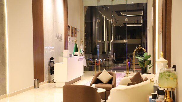 A modern reception area with a reception desk, seating area, and a decorative lamp. - Afal Serviced Apartments - Al-Munsiyah (Riyadh)