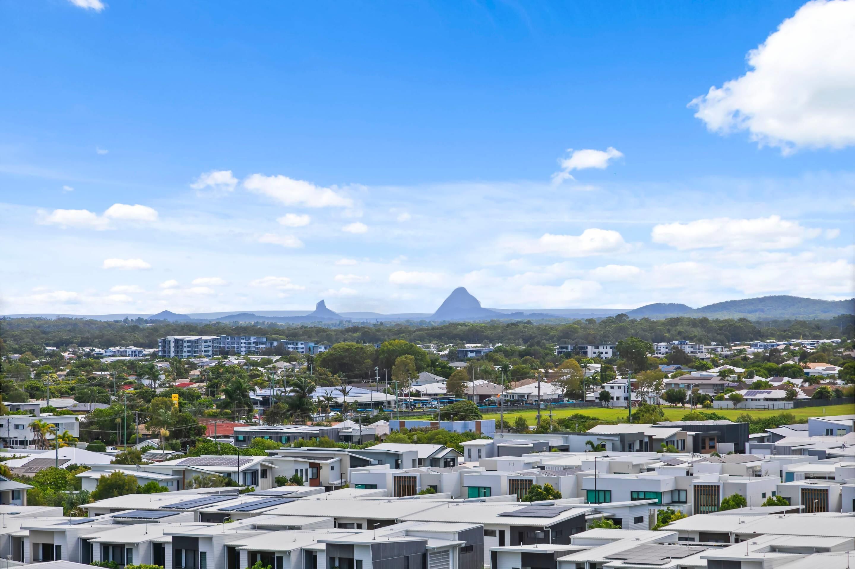 A residential area with modern houses, a clear sky, and distant mountains.