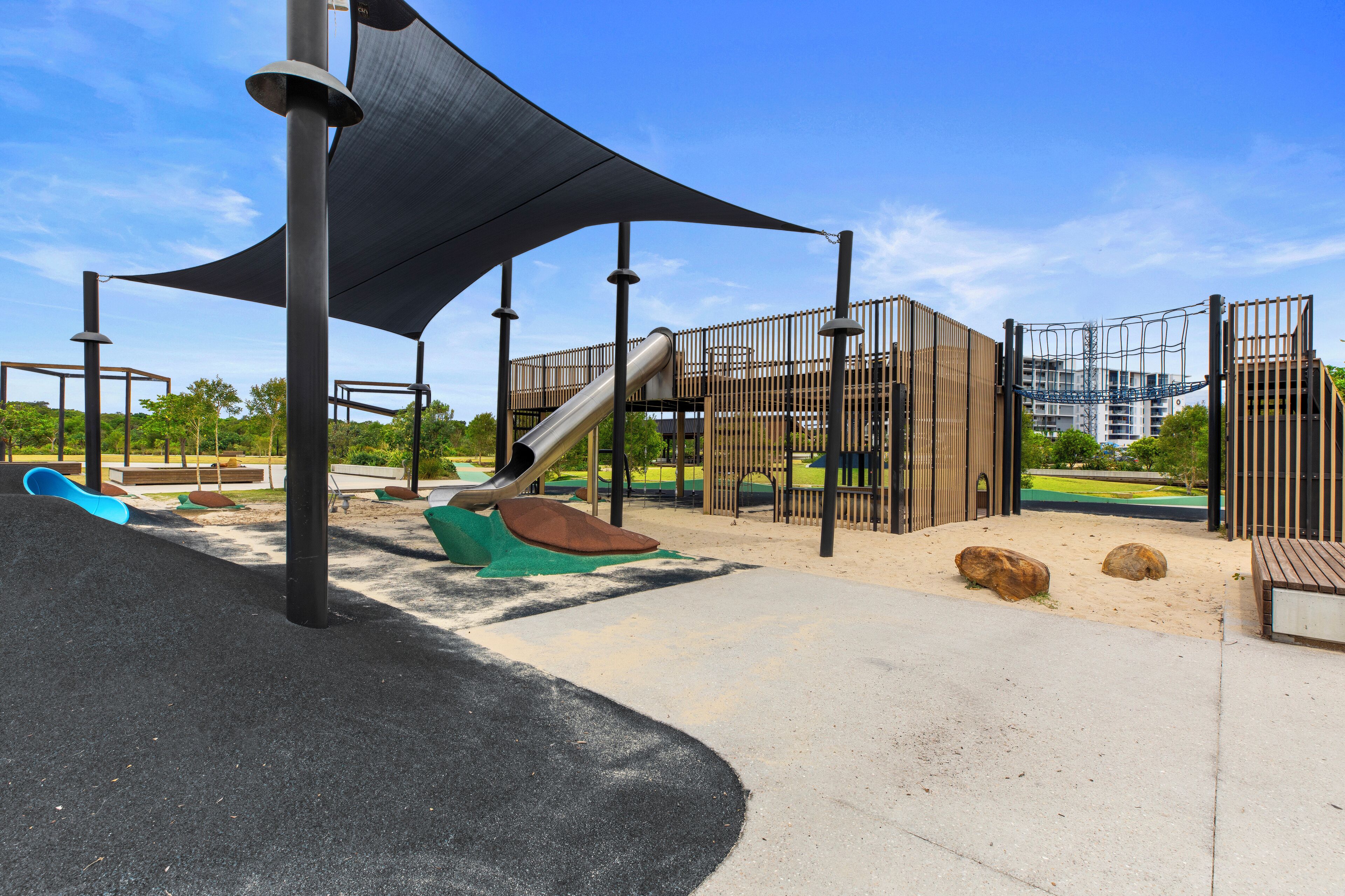 A playground with a slide, climbing structures, and a shaded area.