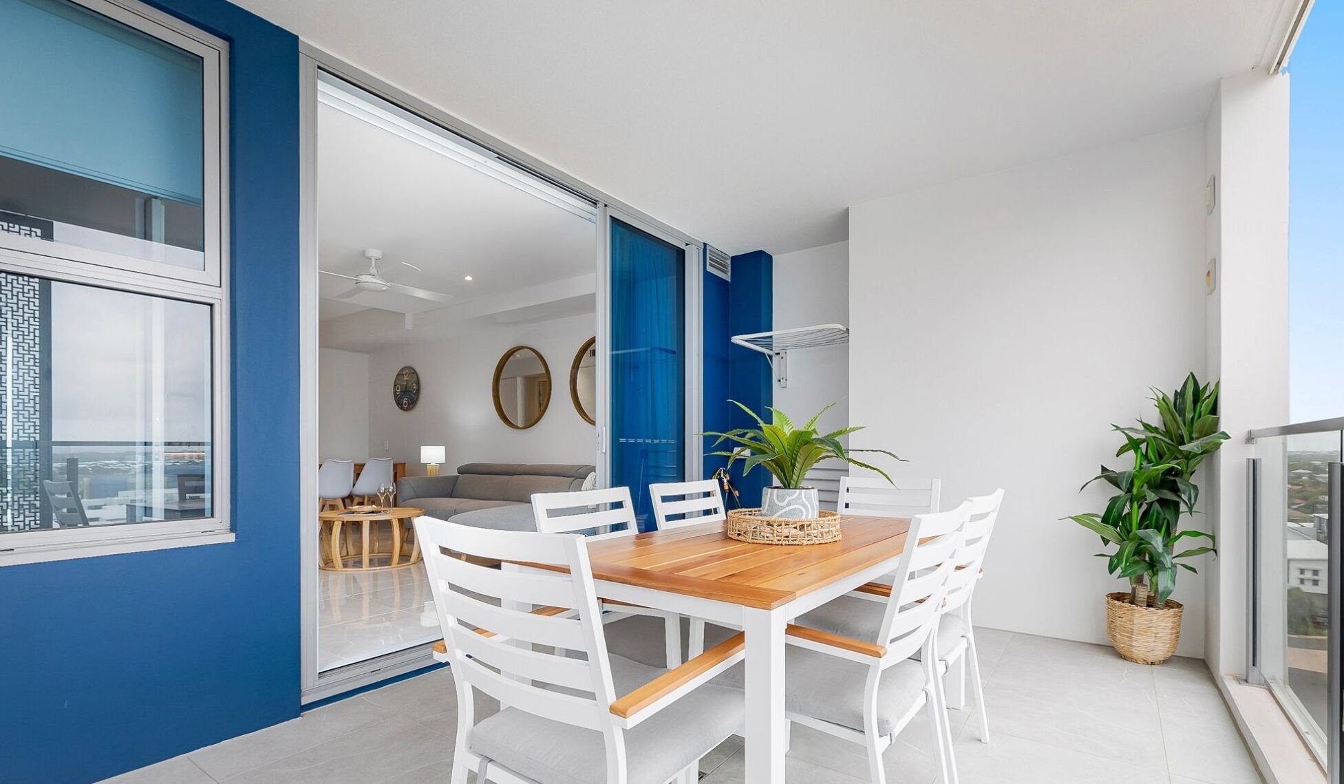 Eine moderne Wohnung mit Essbereich, Wohnzimmer und einem Balkon mit Pflanzen.
