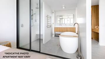 A modern bathroom with a glass shower enclosure, a freestanding bathtub, and a wooden vanity.