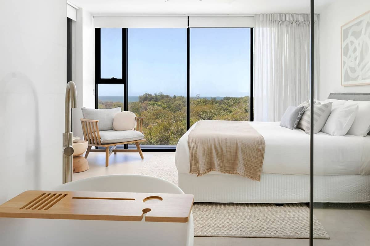 Enjoy a serene view from the large window, with a comfortable bed and stylish seating area.