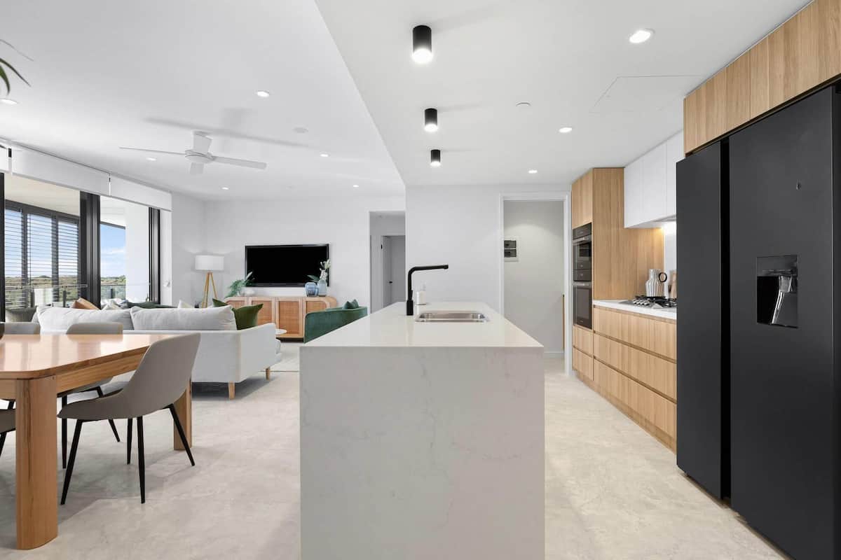 Una cocina moderna con una isla central, armarios de madera y un refrigerador negro.