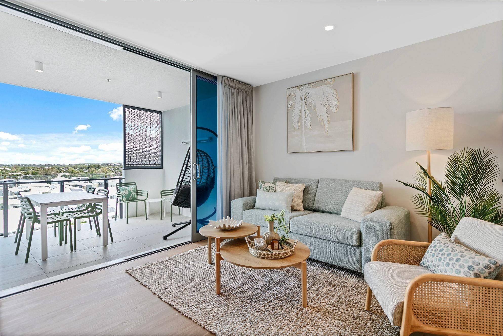 A modern living room with a sofa, a coffee table, and a balcony with outdoor furniture.
