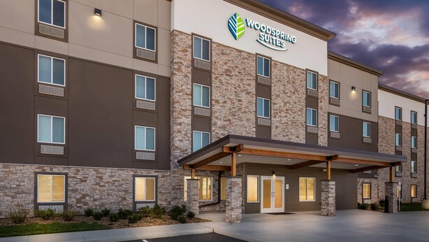 A multi-story hotel with a stone facade and a covered entrance. - WoodSpring Suites St Peters-OFallon (St. Peters)