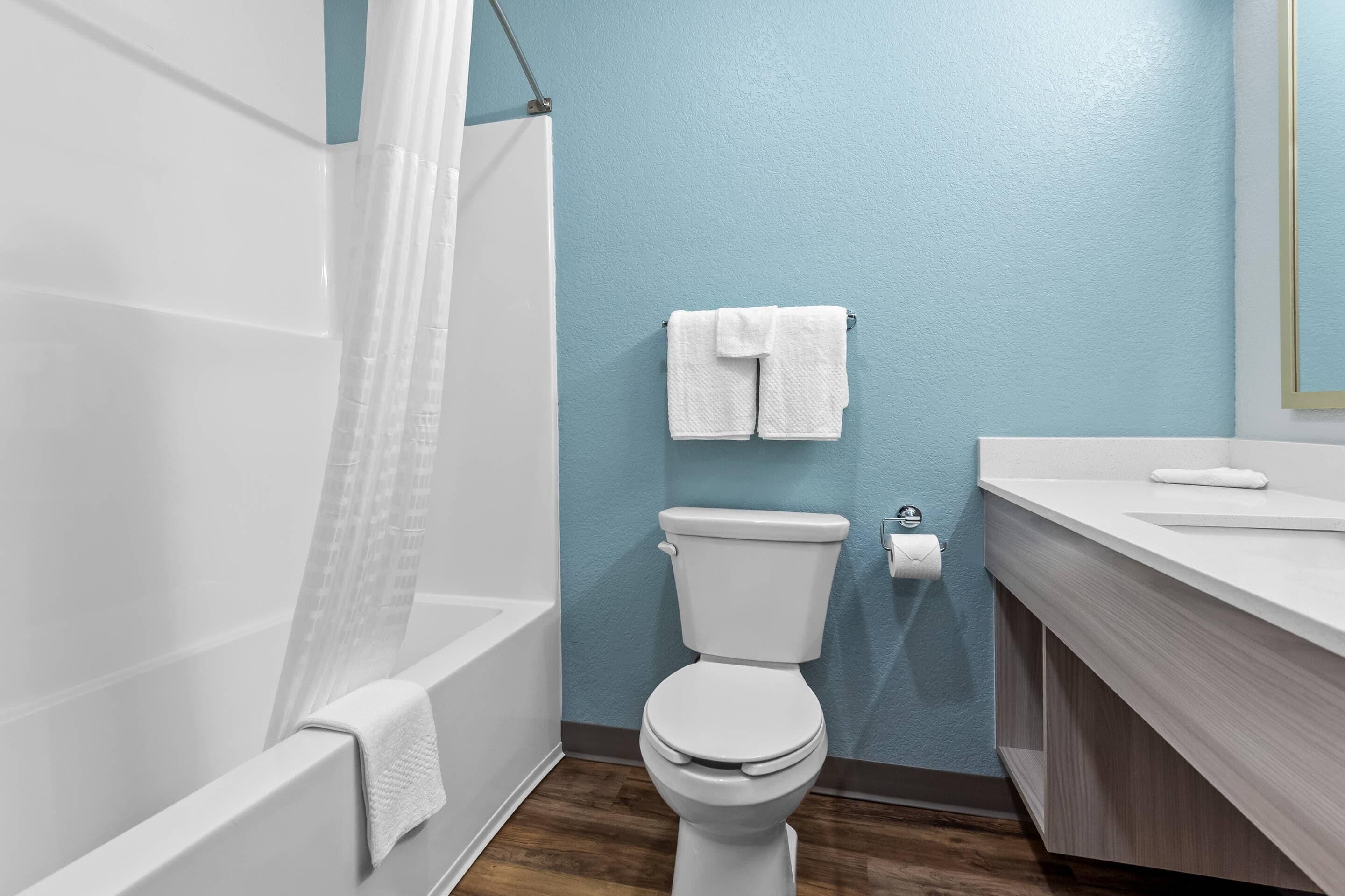 A bathroom with a white toilet, a bathtub with a white towel, and a sink with a white countertop.
