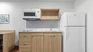 Une cuisine compacte équipée d’un four à micro-ondes, d’un évier encastré et d’un réfrigérateur.