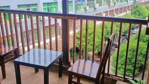Ein Balkon mit Blick auf eine Wohngegend, ausgestattet mit einem Tisch und zwei Stühlen.