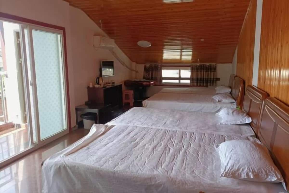 A room with two beds, a desk, a chair, a window with curtains, and a sliding glass door.