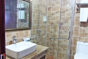 Un bany amb dutxa envidriada, un lavabo blanc i un mirall amb marc daurat.