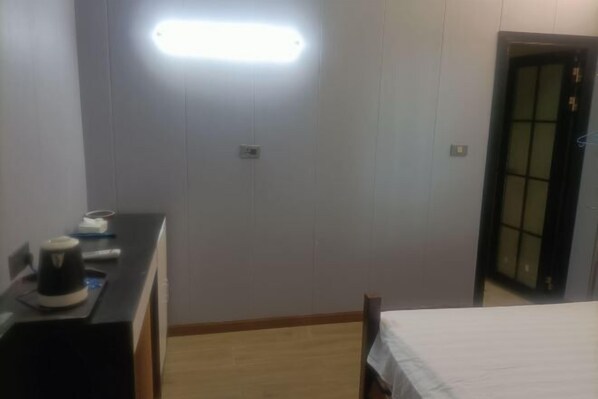 Habitació d'hotel amb llit, escriptori amb una paperera i llum penjant lluminosa.