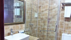 Ein Badezimmer mit einem weißen Waschbecken, einer Duschkabine aus Glas und einer gefliesten Wand.