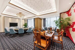 A hotel conference room with a large table, multiple chairs, a television, and a plant. - Rufu Hotel (Ganzhou)