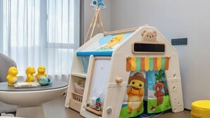 A playhouse with a bear and duck design, a small table with toys, and a window with curtains. - Rufu Hotel (Ganzhou)