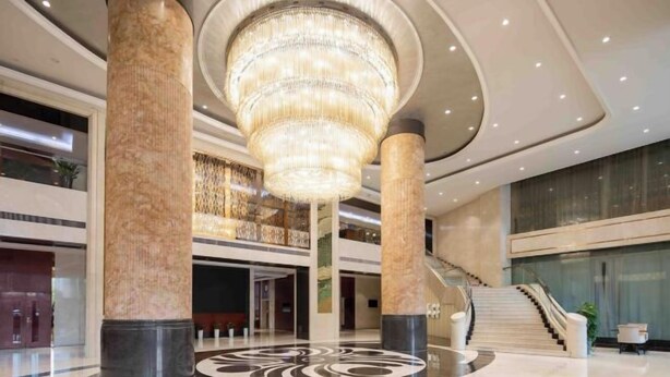 A spacious lobby with a grand chandelier, marble columns, and a central circular design on the floor. - Rufu Hotel (Ganzhou)