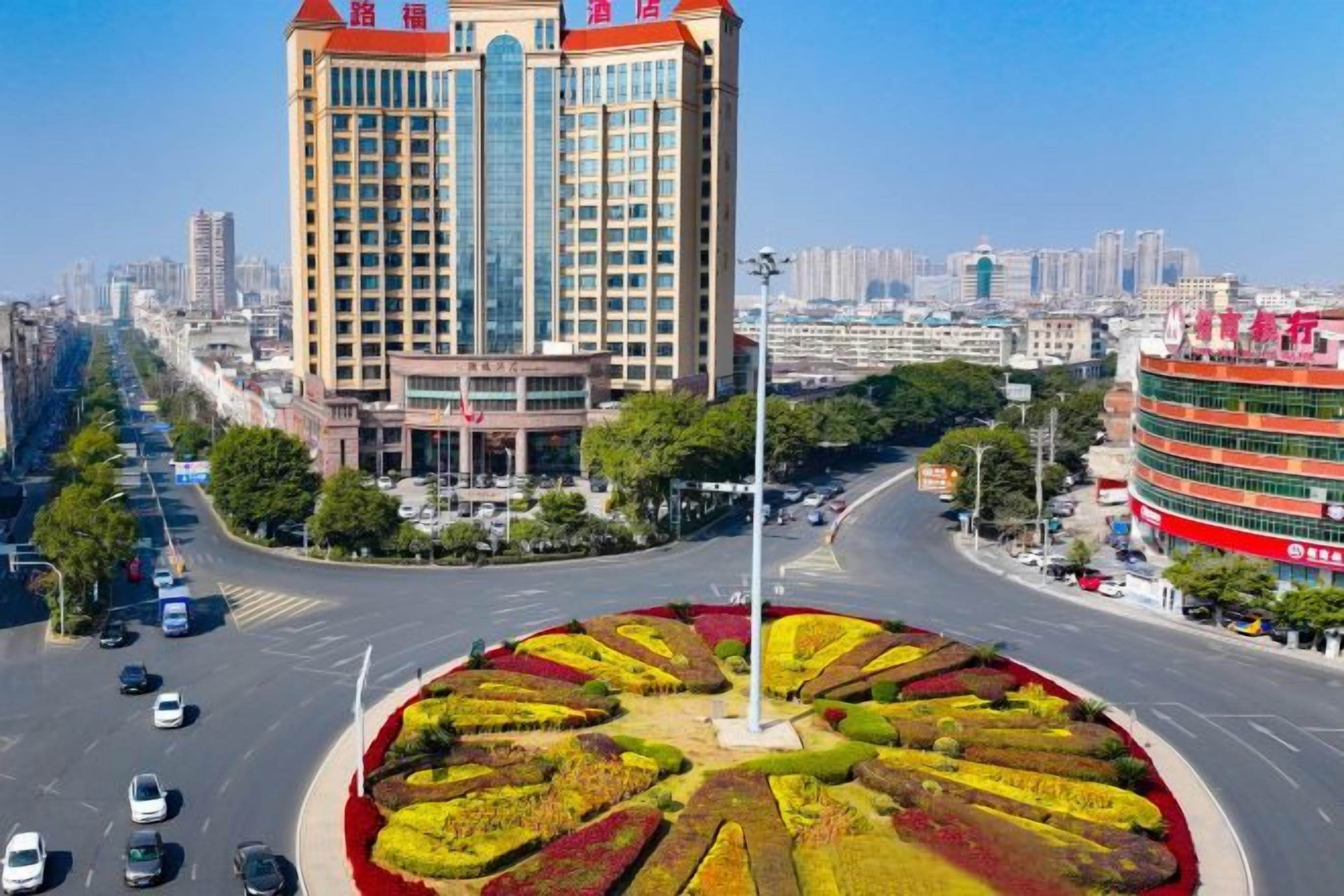 A multi-story building with a central courtyard and a roundabout with landscaped gardens.